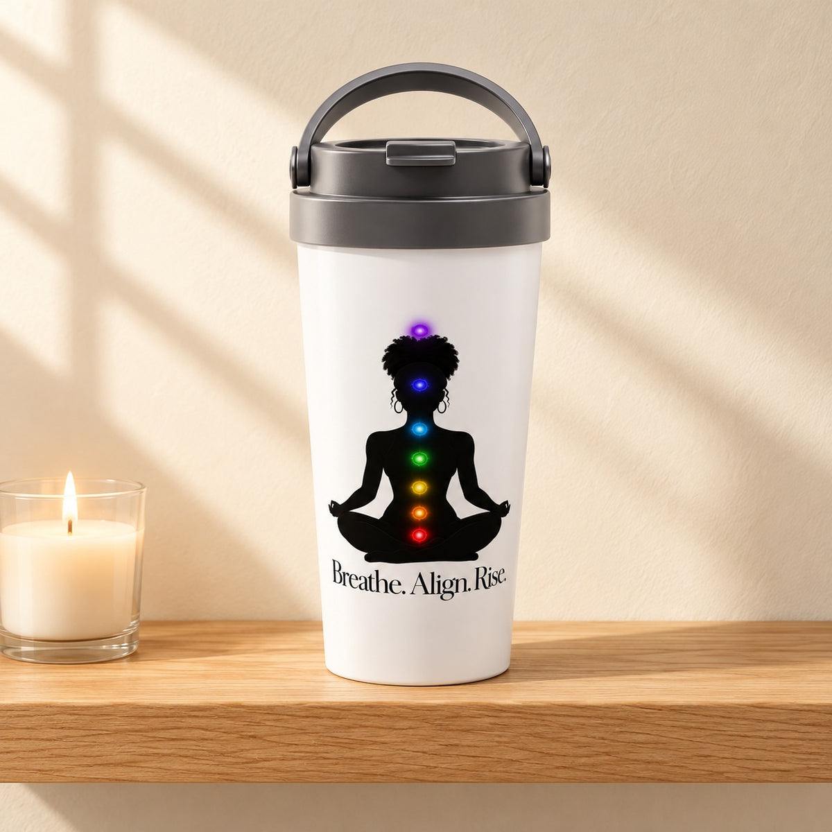Breathe. Align. Rise. 15 oz white travel mug with a meditating woman silhouette and glowing chakra lights, standing on a light oak shelf beside a white candle