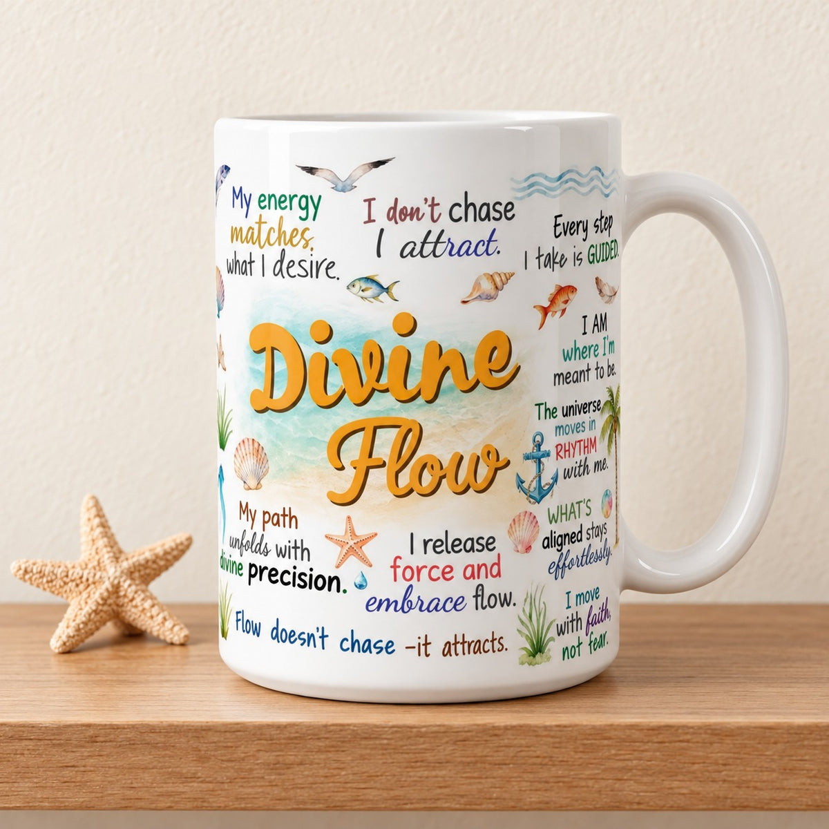 Divine Flow 15 oz white mug with the golden title facing forward over a sea and sand watercolour, ocean affirmations around it, on a light oak shelf beside a starfish