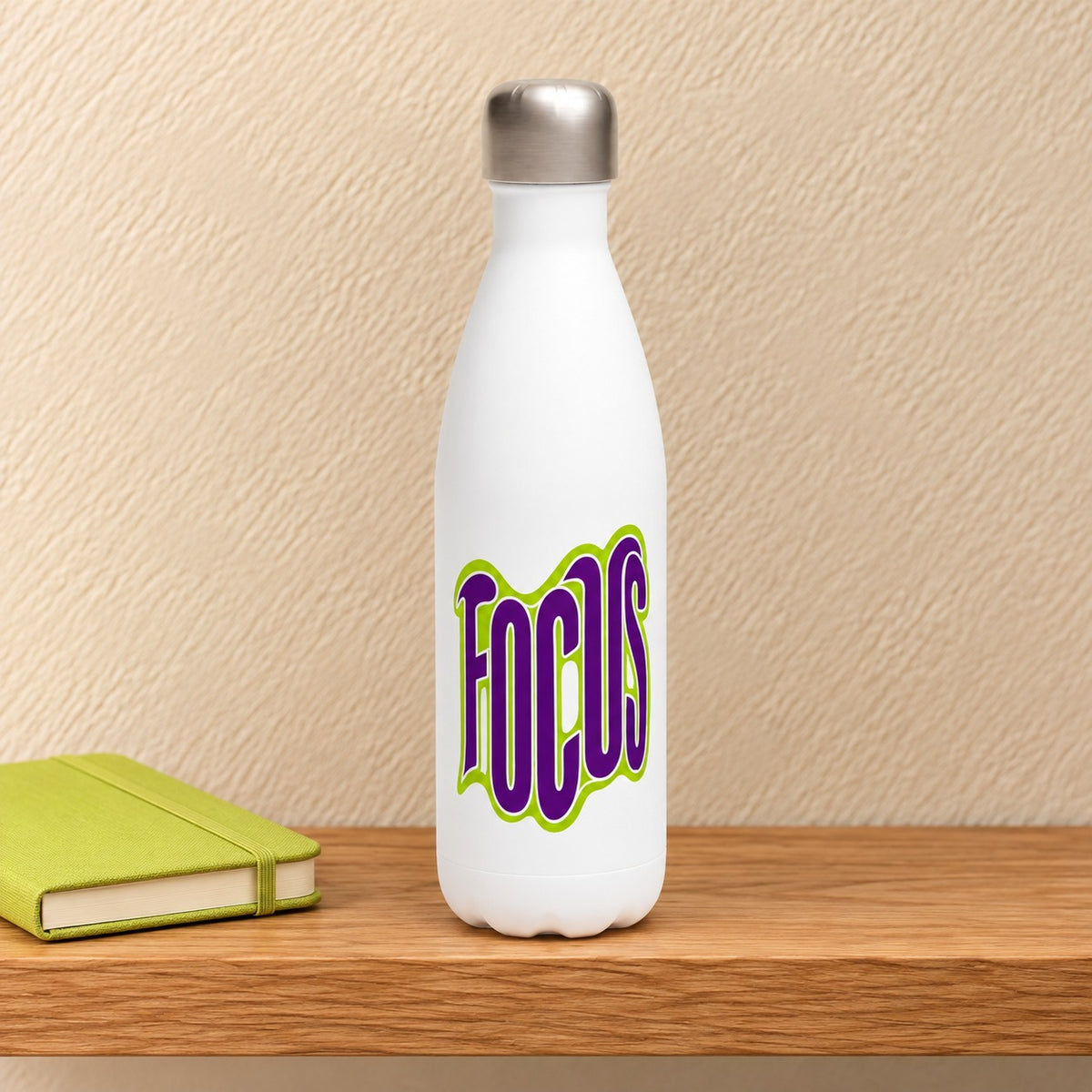 Focus 17 oz white water bottle with bold purple FOCUS lettering in a lime outline, standing on a light oak shelf beside a lime notebook