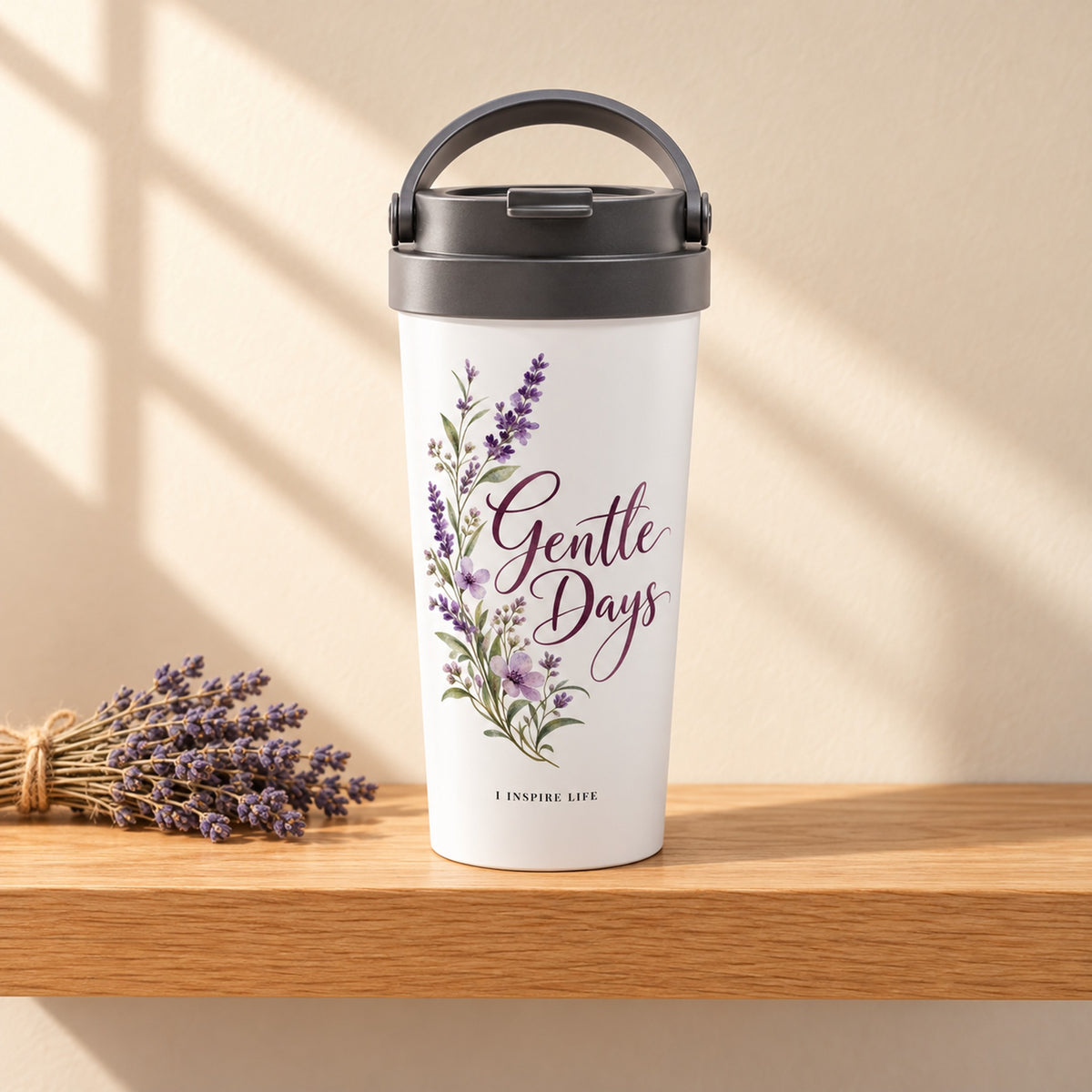 Gentle Days 15 oz white stainless steel travel mug on a light oak shelf beside a bundle of dried lavender, design facing forward