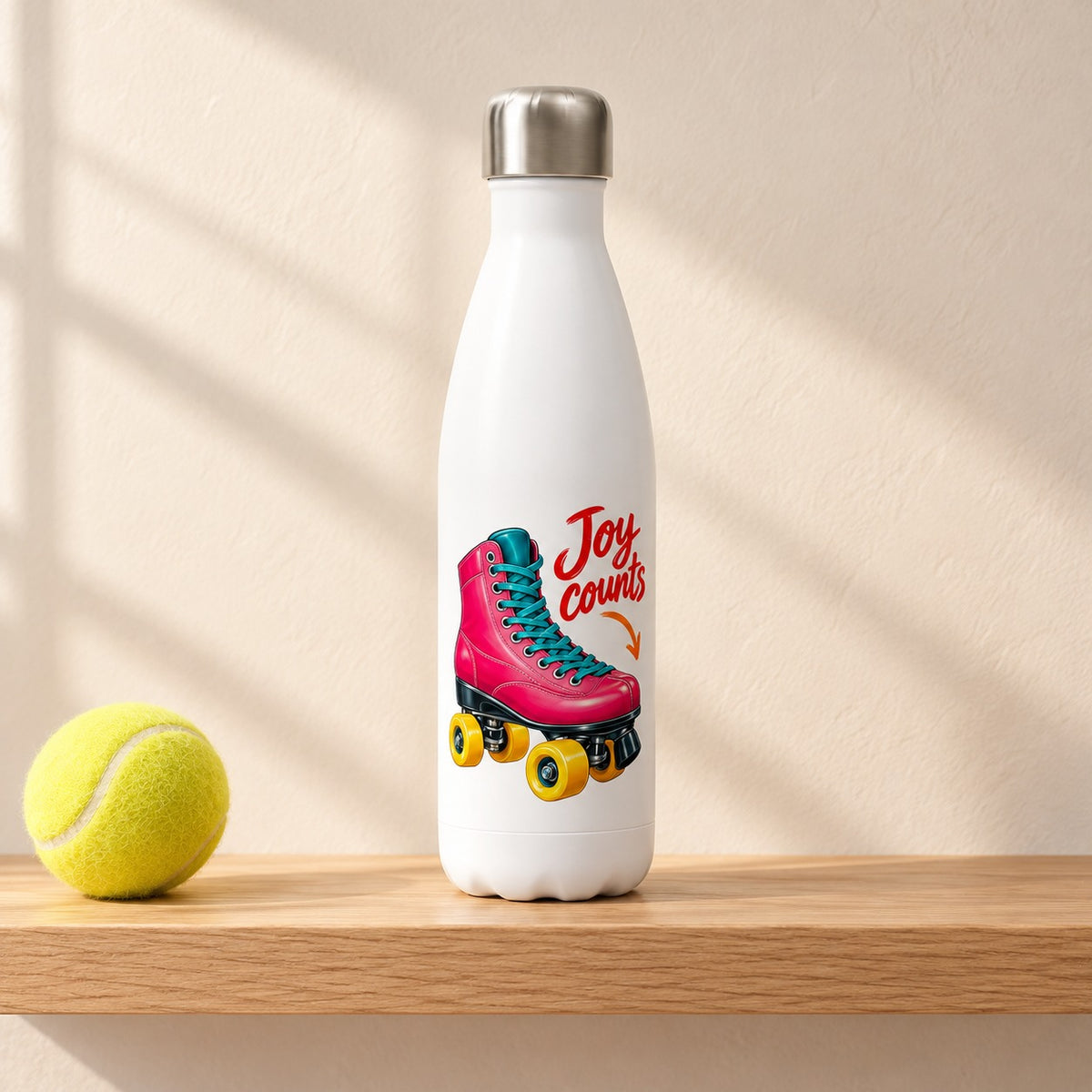 Joy Counts 17 oz white water bottle with a hot pink roller skate and red script, standing on a light oak shelf beside a tennis ball