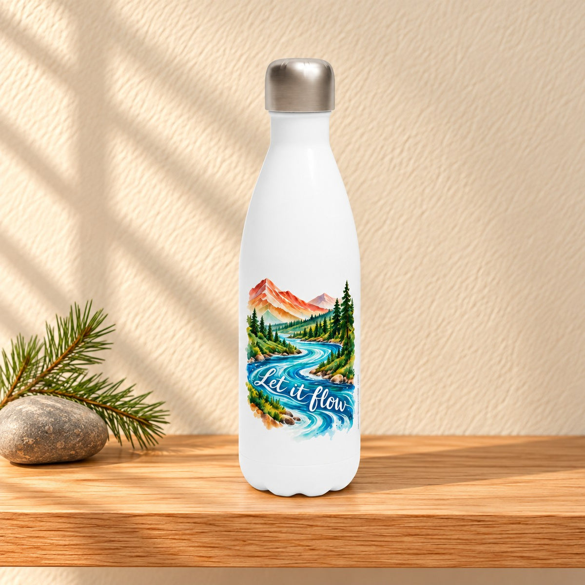 Let It Flow white 17 oz water bottle with a watercolour mountain river and white script, standing on a light oak shelf beside a river stone and pine sprig