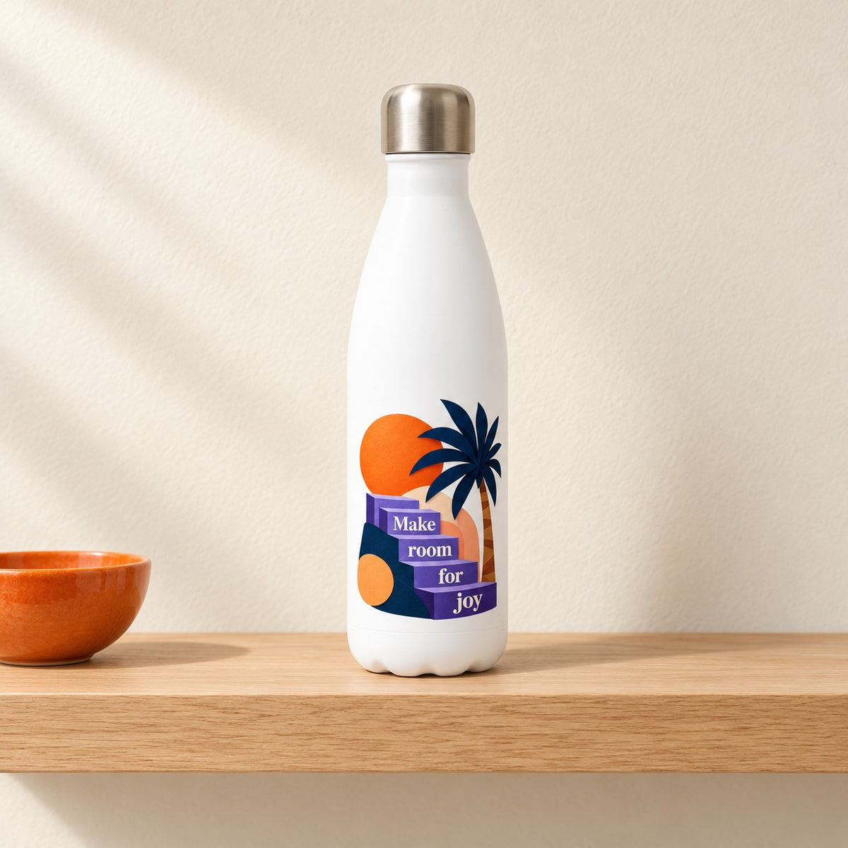 Make Room for Joy white 17 oz water bottle with a cut paper sun, palm tree and purple steps, standing on a light oak shelf beside an orange bowl