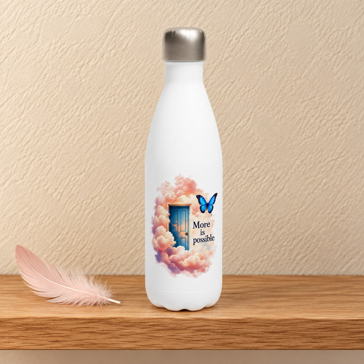 More Is Possible 17 oz white water bottle with a blue door in pink clouds and a butterfly, standing on a light oak shelf beside a pink feather