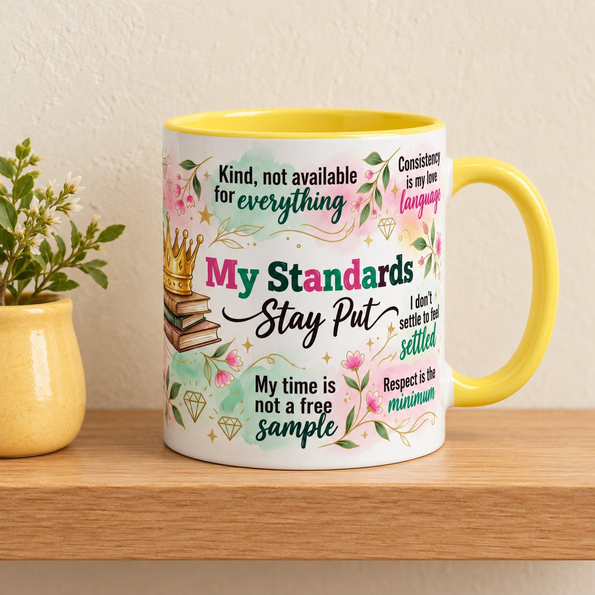 My Standards Stay Put 11 oz mug with a yellow handle and yellow inside, title facing forward, resting on a light oak shelf beside a small plant in a yellow pot