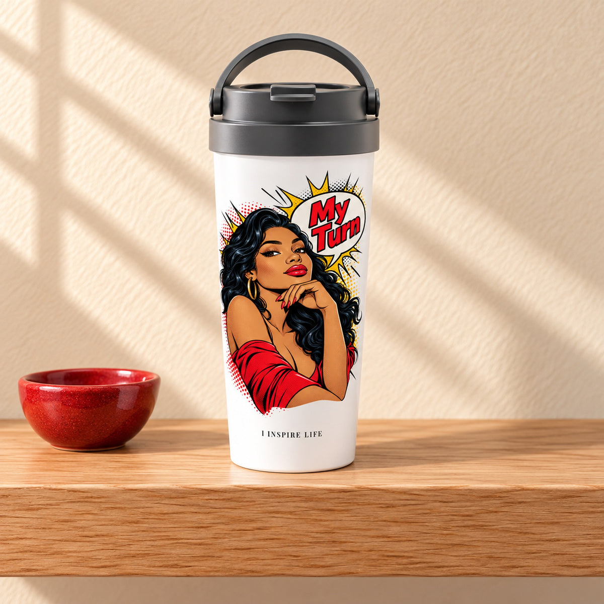 My Turn 15 oz white stainless steel travel mug on a light oak shelf beside a small red ceramic bowl, design facing forward