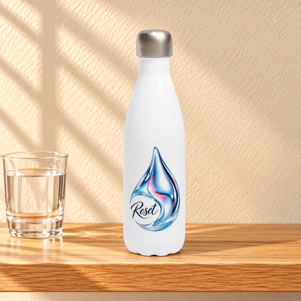 Reset white 17 oz water bottle with a chrome blue water drop and the word Reset, standing on a light oak shelf beside a glass of water