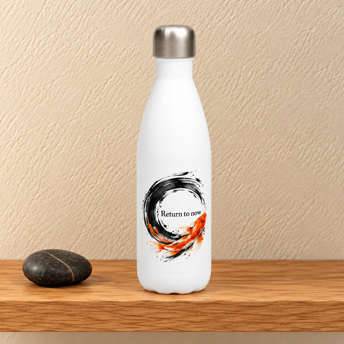Return to Now 17 oz white water bottle with a black ink enso circle and orange koi, standing on a light oak shelf beside a black stone
