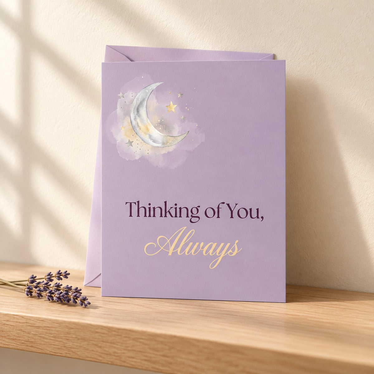 Thinking of You, Always card in soft lilac with a watercolour crescent moon, standing on a light oak shelf beside dried lavender