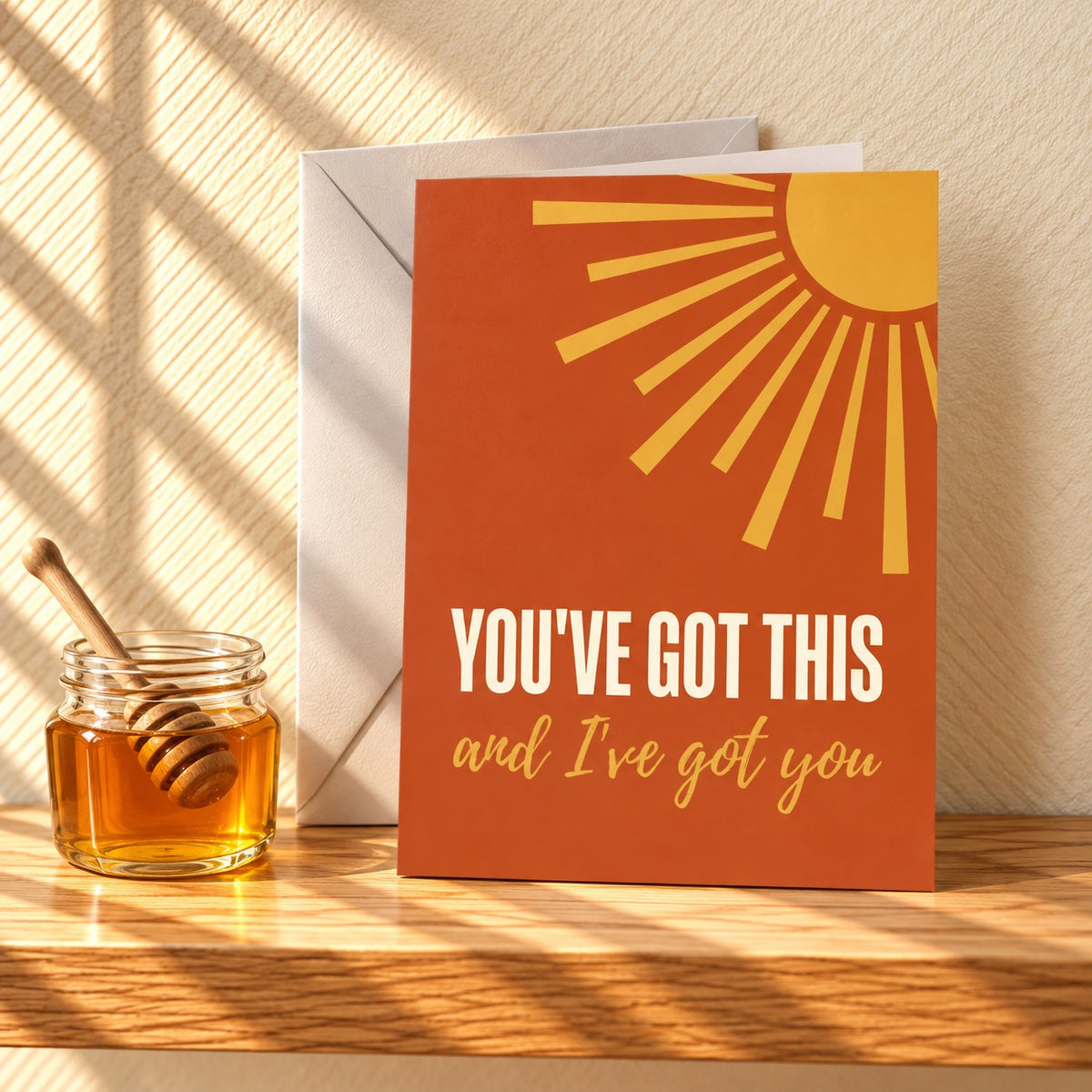 You've Got This and I've got you encouragement card in burnt orange with a golden sun, standing on a light oak shelf beside a jar of honey